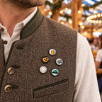Mann in Trachtenweste mit 5er Bayern Pin Set mit Bierkrug, Brezel, Akkordeon, Weißwurst und Trachtenhut für Oktoberfest und Volksfest