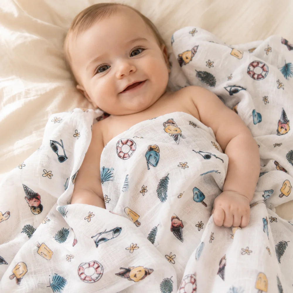 Lächelndes Baby mit Mulltuch im sommerlichen Design Beach Day