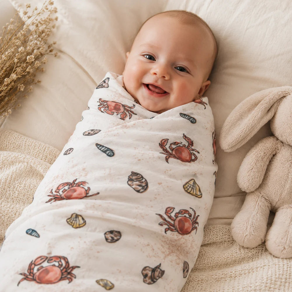 Lächelndes Baby eingewickelt in ein Mulltuch im Design Sealife