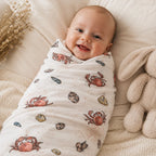 Lächelndes Baby eingewickelt in ein Mulltuch im Design Sealife