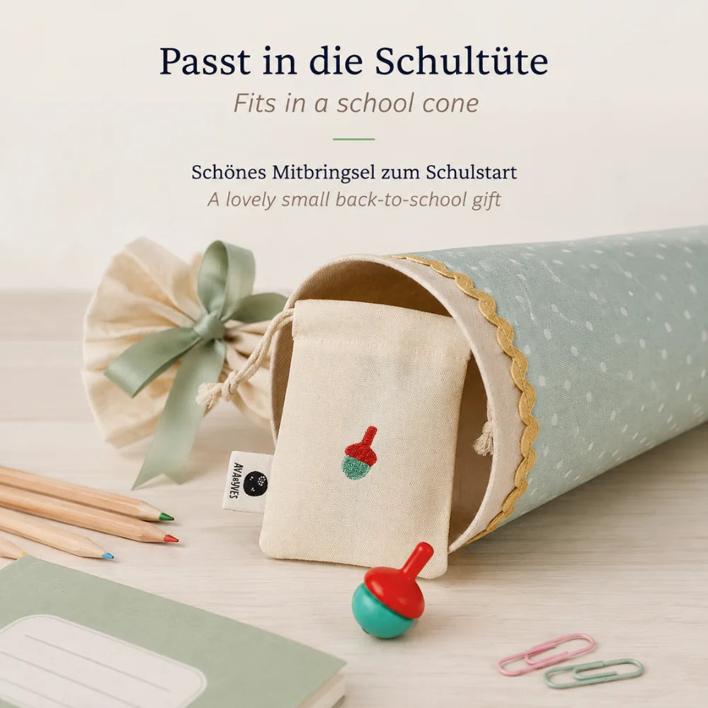 Holzkreisel im Baumwollbeutel neben einer Schultüte – kleines Mitbringsel zum Schulstart