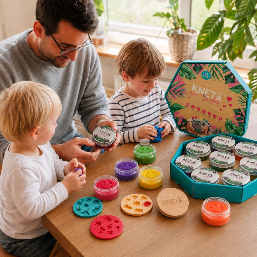 Vater und zwei Kinder spielen gemeinsam mit veganer KNETÄ Kinderknete am Tisch