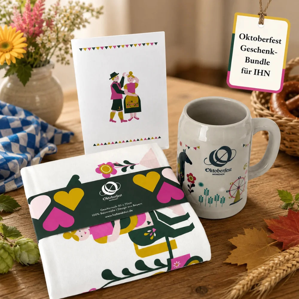 Oktoberfest-Geschenkbundle für ihn mit Bierkrug, Geschirrtuch und Postkarte auf herbstlich dekoriertem Holztisch.