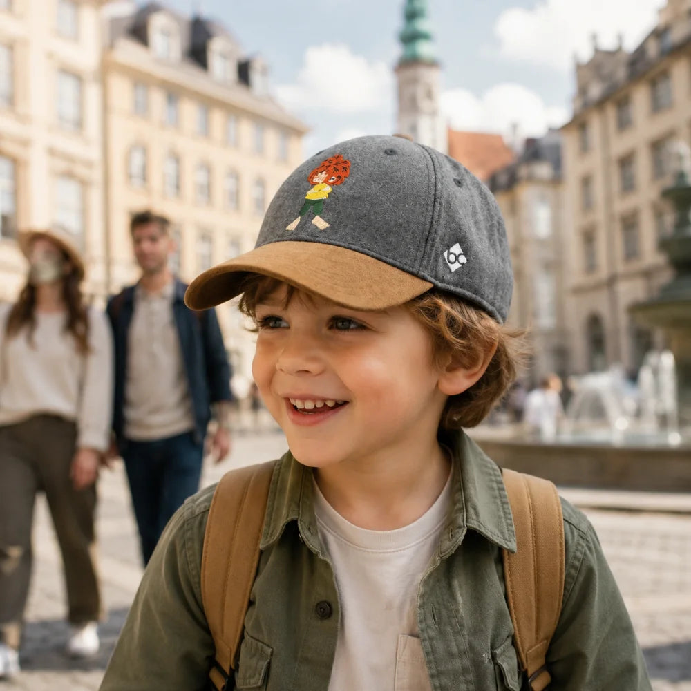 Kind trägt graue Pumuckl Kinder-Cap mit braunem Schirm bei einem Stadtbummel