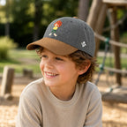 Lachendes Kind trägt die graue Pumuckl Kinder-Cap auf dem Spielplatz
