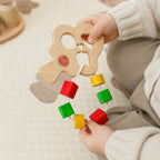 Baby spielt mit buntem Steckbaum aus Holz