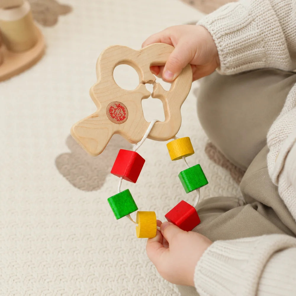 Baby spielt mit buntem Steckbaum aus Holz