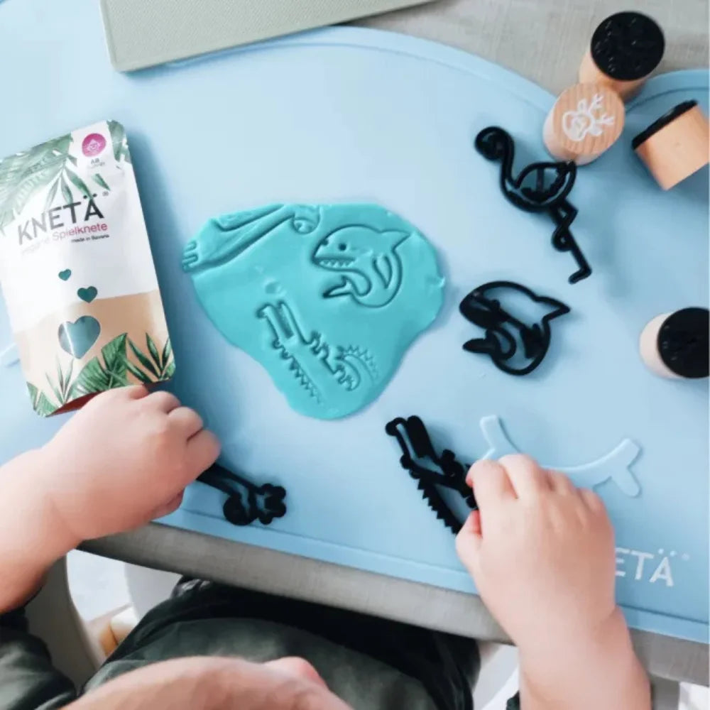 Kind spielt kreativ mit Knete auf der KNETÄ Silikon-Tischunterlage am Kindertisch