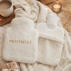 EFIE Wärmflasche „Frostbeule“ mit goldener Stickerei, herausnehmbarer Innenflasche und Geschenkverpackung in warmer Umgebung.