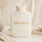 EFIE Wärmflasche „Frostbeule“ mit weichem Bio-Baumwollbezug und goldfarbener Stickerei auf hellem Hintergrund.