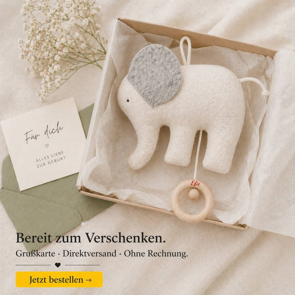 Elefanten-Spieluhr in Geschenkbox mit Seidenpapier, Grußkarte und Blumen als Geschenk zur Geburt stilvoll arrangiert