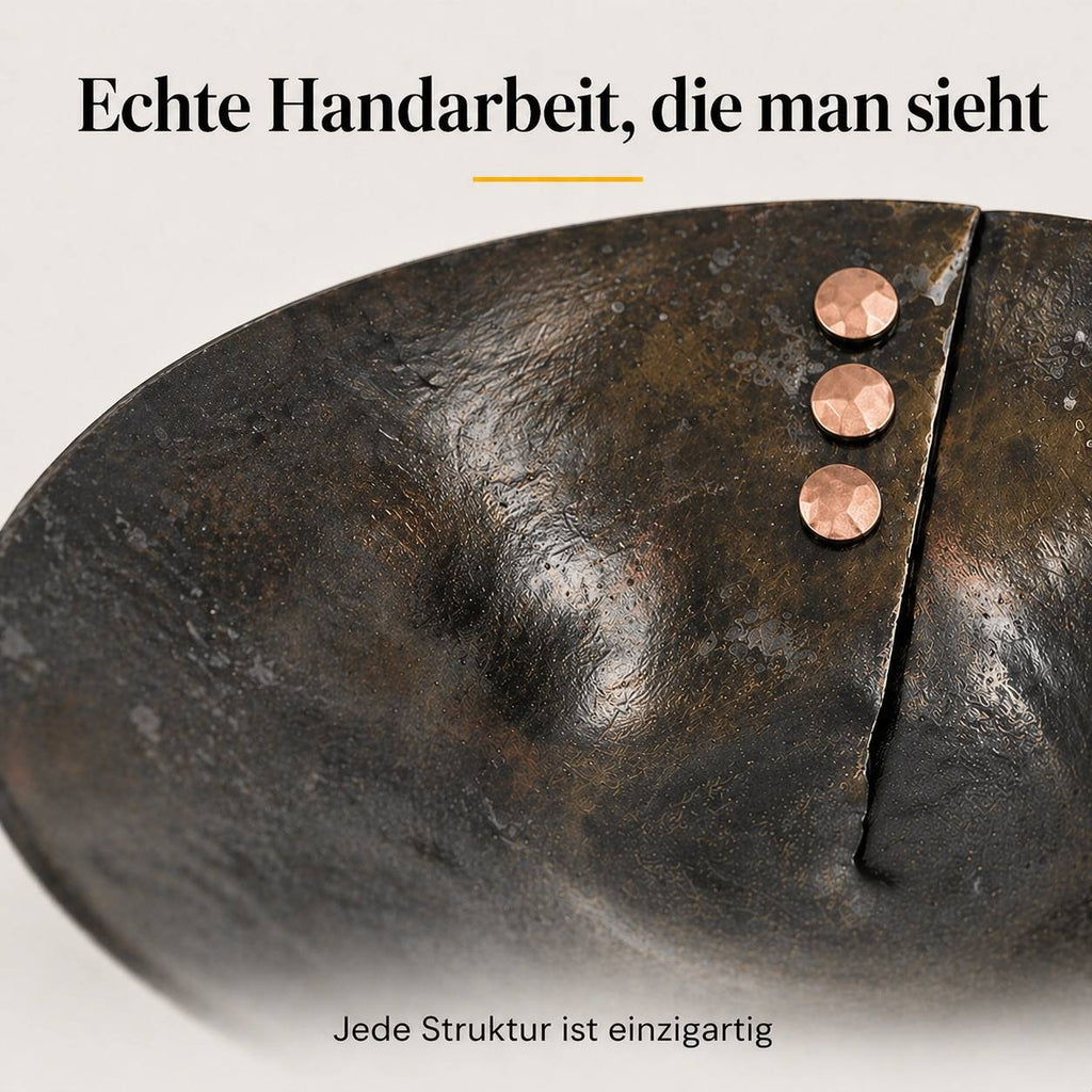 Detailaufnahme einer handgeschmiedeten Eisenschale mit strukturierter Oberfläche, Bruchkante und drei Kupfernieten
